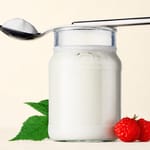 Naturquark im Glas mit Löffel und Himbeeren